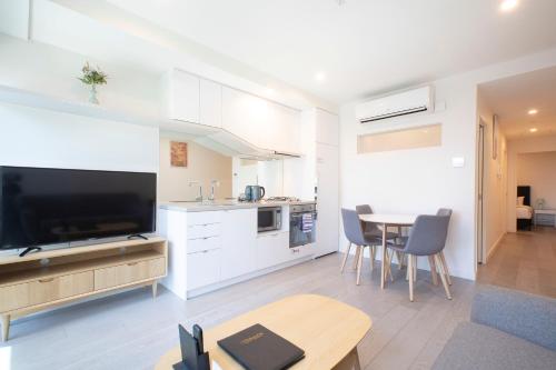a kitchen and living room with a large television and a table at Platinum City Serviced Apartments in Melbourne
