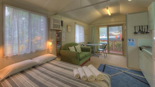 a bedroom with a bed and a living room at Flying Fish Point Tourist Park in Innisfail