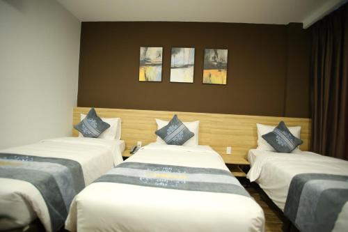 three beds in a room with three paintings on the wall at KingSales Hotel in Thanh Hóa