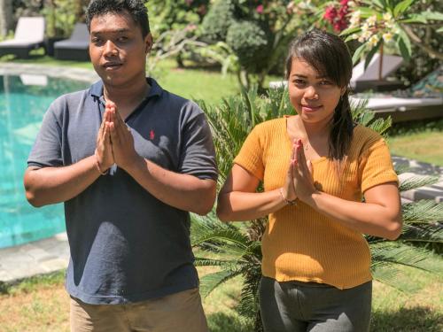 a man and a woman praying in front of a pool at Villa Rizki Candidasa in Candidasa