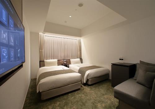 a hotel room with two beds and a flat screen tv at ORIENTAL HOTEL KYOTO ROKUJO in Kyoto