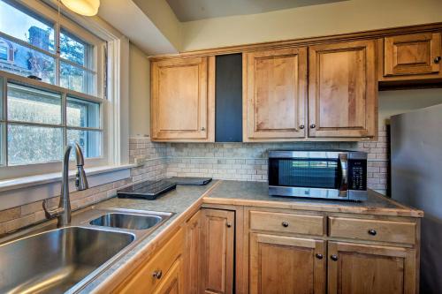 a kitchen with wooden cabinets and a sink and a microwave at 1 Mi to Reading Pagoda Cozy Apt with Patio Access! in Reading
