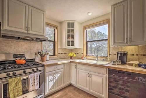 a kitchen with white cabinets and a stove at Artists Retreat with Pecos National Park Views! in Rowe