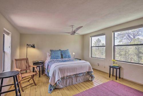 a bedroom with a bed and a chair and windows at Artists Retreat with Pecos National Park Views! in Rowe