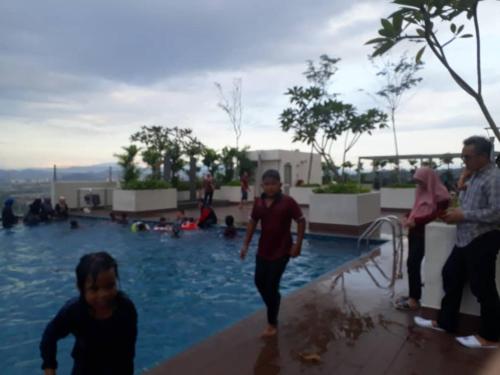 a group of people standing around a swimming pool at hasanah evo studio suites in Kampong Sungai Ramal Dalam