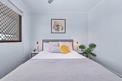 1 dormitorio blanco con 1 cama blanca grande y 2 mesas en Modern Beach Front Apartment, en Airlie Beach
