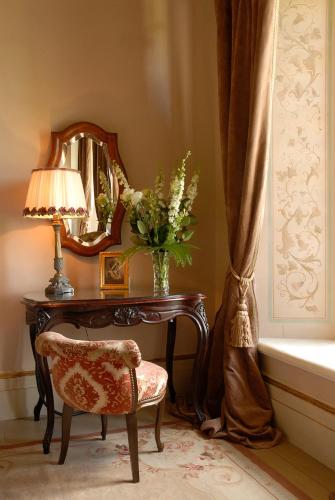 a table with a vase of flowers and a mirror at Borgo Santo Pietro in Chiusdino