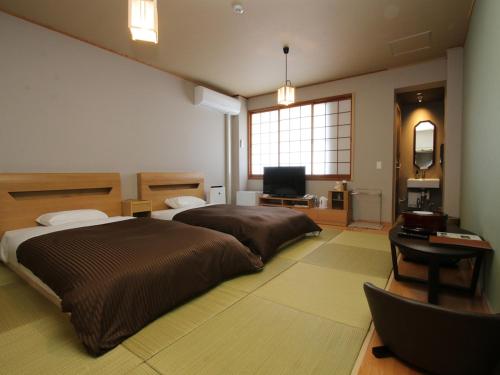 1 dormitorio con 2 camas, escritorio y TV en Kafutei en Yamaga