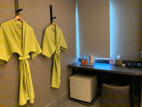 une chambre d'hôtel avec des serviettes jaunes suspendues sur un mur dans l'établissement Tango Vibrant Living Hotel - SHA Extra Plus, à Bangkok