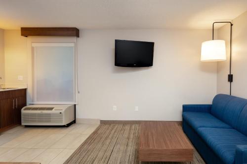 a living room with a couch and a tv on a wall at Holiday Inn Express & Suites Milton East I-10 by IHG in Milton