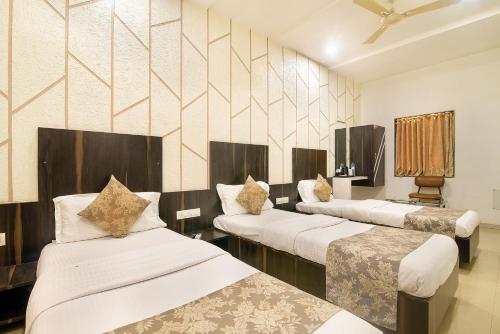 una camera con tre letti di Hotel Satkar a Surat