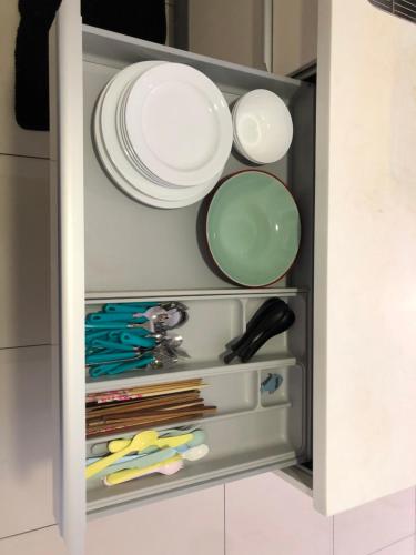 a cabinet with plates and utensils in it at Icon City 8Pax SunwayPyramid & Lagoon CityView in Kuala Selangor