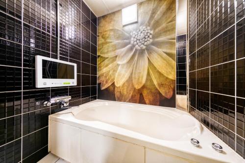 a bathroom with a tub and a tv on the wall at HOTEL LUNA MODERN Sakuranomiya (Adult Only) in Osaka