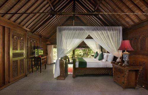 Ayung Resort Ubud في بيانغان: غرفة نوم بسرير مع مظلة