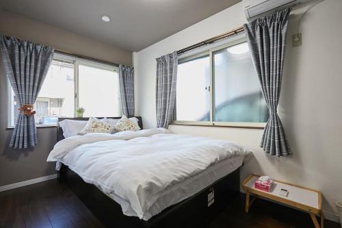 ein Schlafzimmer mit einem großen Bett und zwei Fenstern in der Unterkunft Ka's house in Tokio