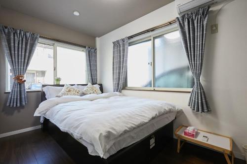 a bedroom with a large bed and two windows at Ka's house in Tokyo