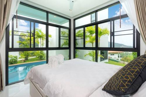 a bedroom with a large bed and large windows at 360 Degree Kamala Seaview Villa in Kamala Beach