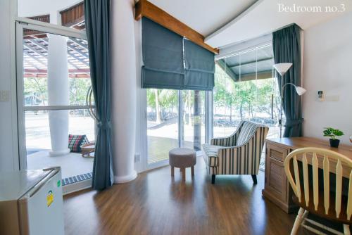 Koh Mak Cococape Resort في كو ماك: غرفة معيشة مع مكتب وكراسي ونوافذ