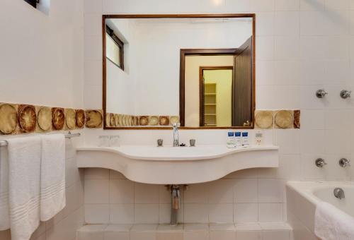 a bathroom with a sink and a tub and a mirror at Malaga Hotel in Panorama