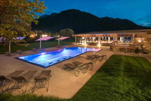 einen Pool mit Stühlen und ein Haus in der Unterkunft Ferienhotel Tyrol Söll am Wilden Kaiser in Söll
