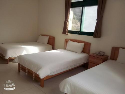 a room with two beds and a window at Jiou Wu Siao Jhu in Nangan