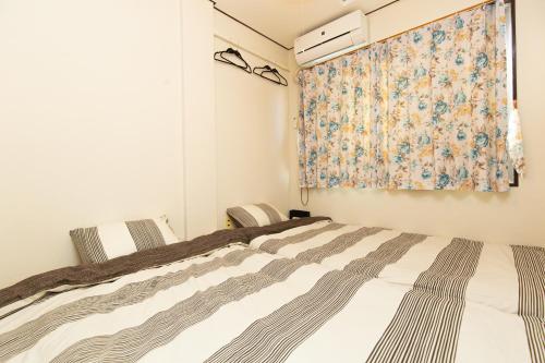 1 dormitorio con cama y ventana con cortina en Daiichi ichiba Building, en Tokio