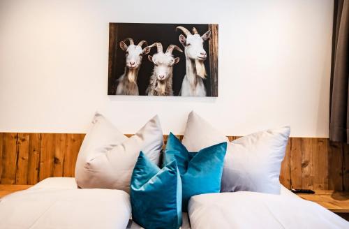 a room with a couch with pillows and a picture of goats at Allmi Appartement in Sankt Gallenkirch
