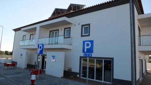 a white building with blue parking signs in front of it at Hotel Baleal Spot in Baleal