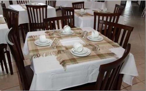 a table with a white table cloth and wooden chairs at Pousada das Orquídeas in Pirenópolis