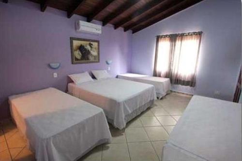 a hotel room with two beds and a window at Pousada das Orquídeas in Pirenópolis
