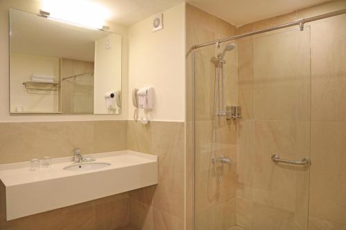 uma casa de banho com um lavatório e um chuveiro em Lacosta Hotel em Aqaba