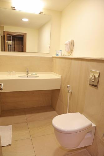 a bathroom with a toilet and a sink and a mirror at Lacosta Hotel in Aqaba