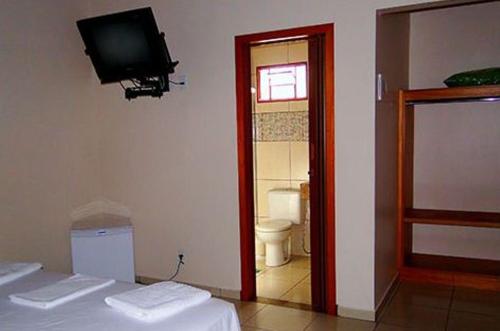 Habitación con cama, TV y baño. en Pousada das Orquídeas, en Pirenópolis