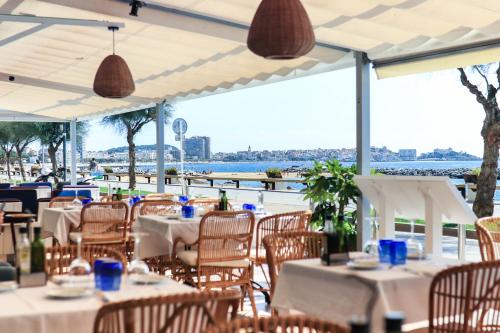 um restaurante com mesas e cadeiras com vista para a água em Hotel Rosamar em Sant Antoni de Calonge