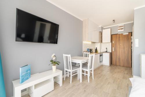 a kitchen and living room with a table and a television at Apartamenty Flamingo by Renters in Międzyzdroje