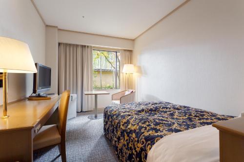 a hotel room with a bed and a desk and a television at Ranzan in Kyoto