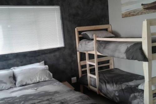 a bedroom with two bunk beds and a window at Angel's Place by the Sea in Hermanus
