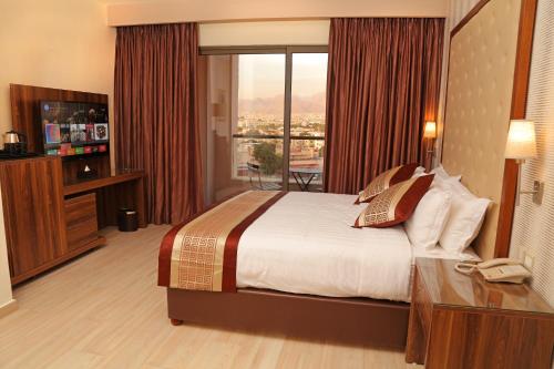 a hotel room with a bed and a large window at Lacosta Hotel in Aqaba