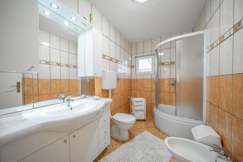 a bathroom with a sink and a toilet and a tub at Adria Sun Apartments in Vodice