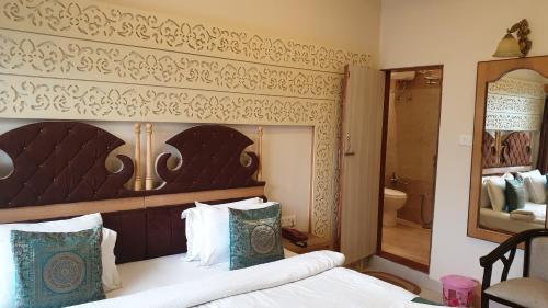 a bedroom with a bed with a wooden headboard and a bathroom at Hotel Temple On Ganges in Varanasi
