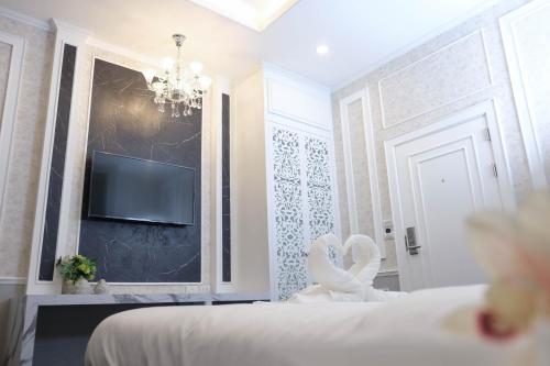 a bedroom with a bed and a tv on a wall at VARIMANTRA HOTEL in Nakhon Pathom