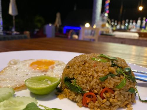 a plate of food with rice and a fried egg and a lime at The Scene Cliff View Villas in Ao Nang Beach