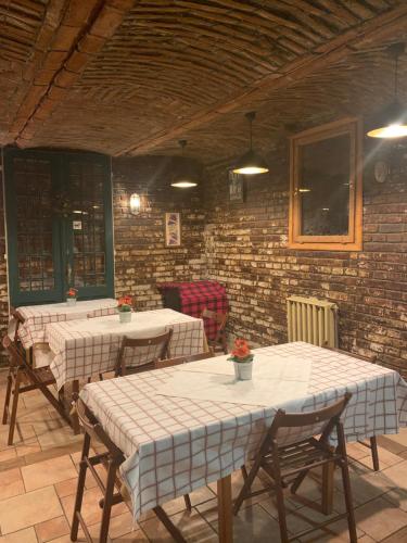 Habitación con mesas, sillas y pared de ladrillo. en Kis Gellért Guesthouse, en Budapest