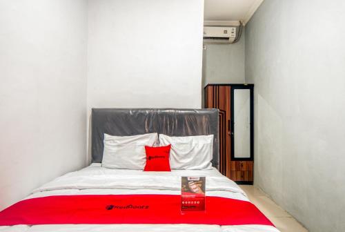 a red pillow on a bed in a room at RedDoorz near Graha Cijantung Mall in Jakarta