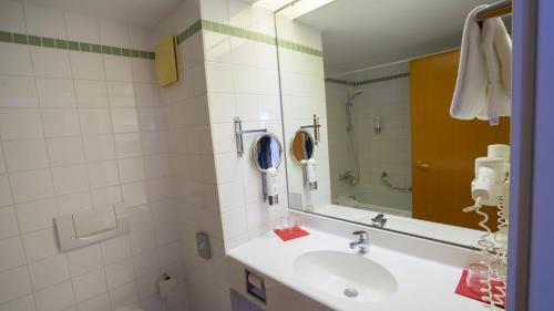
a bathroom with a sink, mirror, and towel rack at Highway Hotel in Herbolzheim
