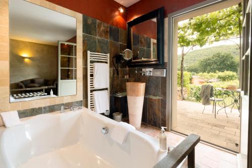 a bath tub in a bathroom with a large window at Hôtel-Spa Le Saint Cirq in Tour-de-Faure