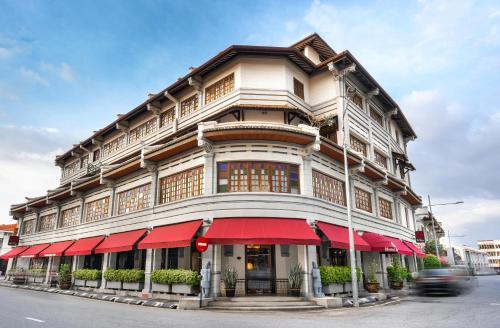 a large building with red awnings on a street at Hotel Penaga in George Town
