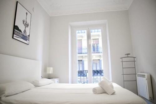 ein weißes Schlafzimmer mit 2 Betten und einem Fenster in der Unterkunft Moraza - Local Rentss in San Sebastián