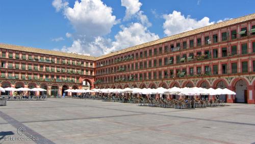 a large brick building with tables and white umbrellas at Apartamento Córdoba centro in Córdoba