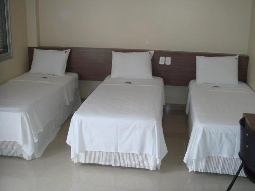 a room with two beds with white linens at Hotel São Paulo in Rondonópolis